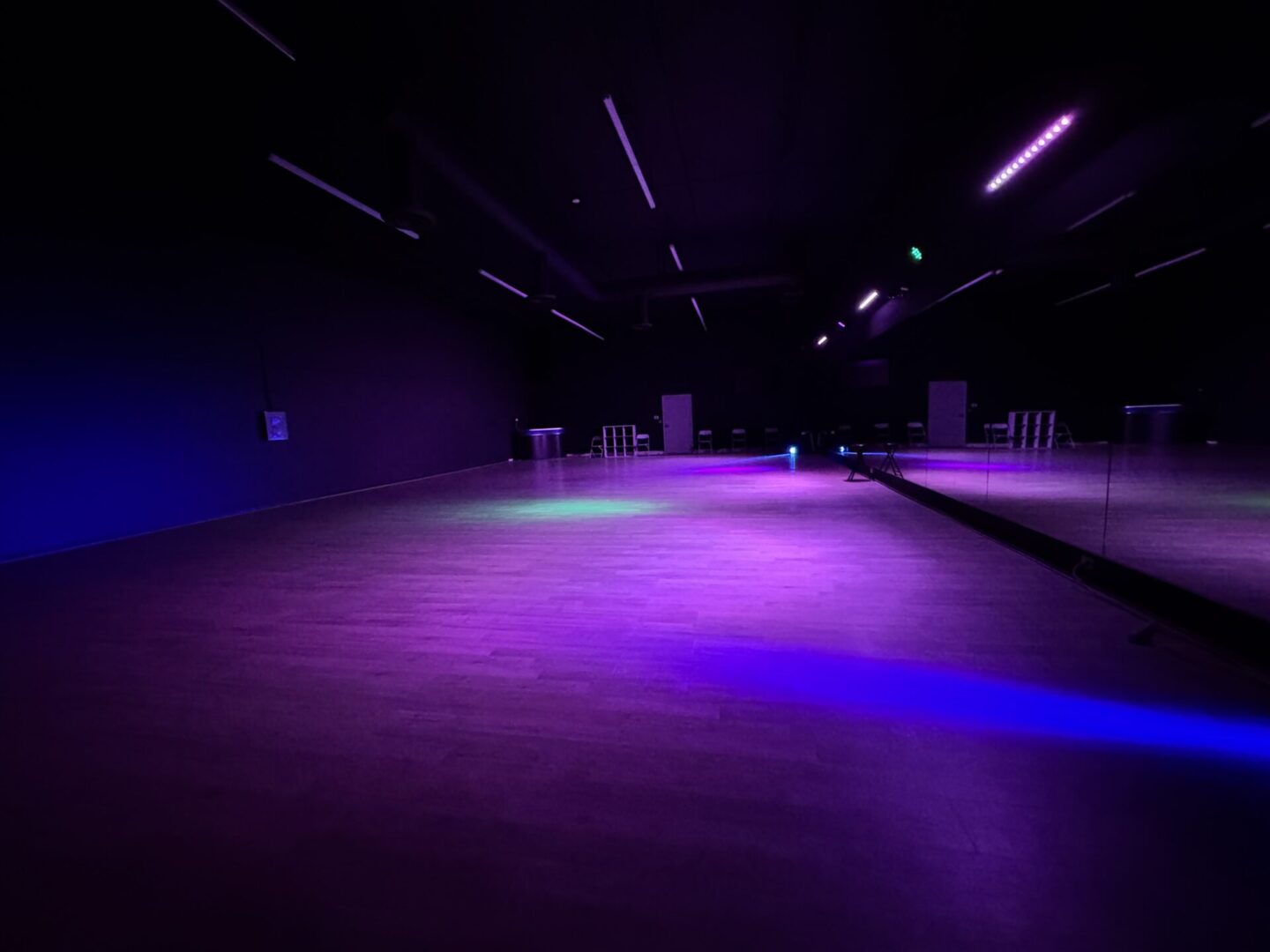 A dark room with purple lights and a black floor.